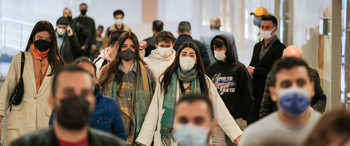 Several people wearing masks walk in the same direction.